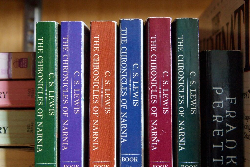 An image showing six Narnia books, by C. S. Lewis, lined up on a bookshelf. The books appear well-read and worn around the edges.